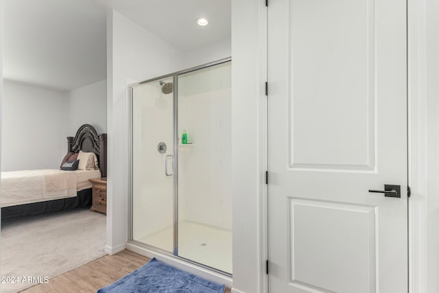 bathroom featuring wood-type flooring and a shower with shower door