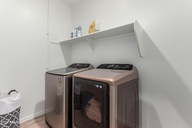 laundry room with light hardwood / wood-style flooring and washing machine and clothes dryer