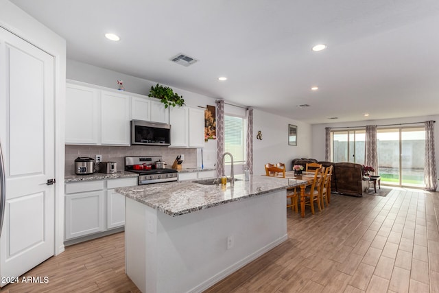 kitchen featuring light wood-type flooring, stainless steel appliances, a kitchen island with sink, sink, and white cabinets