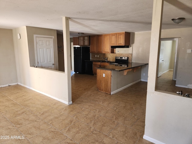 6017 W Colter St, Glendale, AZ 85301 - kitchen with freestanding refrigerator, stainless steel electric stove, a peninsula, tasteful backsplash, and dark countertops