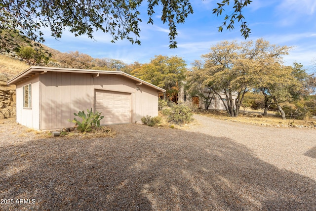 view of home's exterior with a garage, driveway, and an outdoor structure