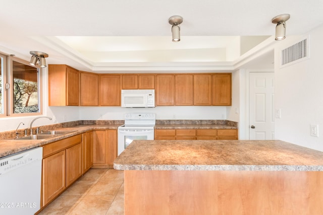 kitchen featuring white appliances, a sink, visible vents, light countertops, and a tray ceiling