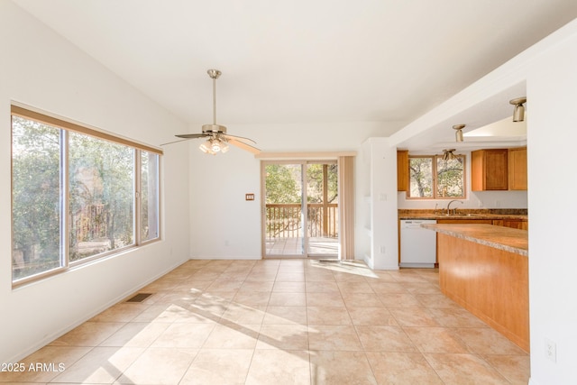 kitchen featuring light tile patterned floors, a sink, visible vents, dishwasher, and brown cabinetry