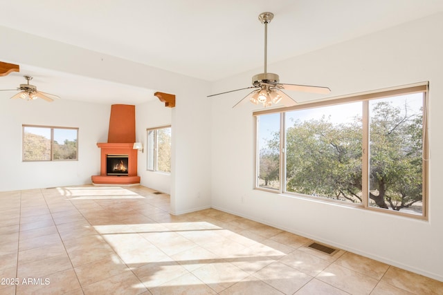 unfurnished living room with ceiling fan, visible vents, a fireplace, and light tile patterned floors