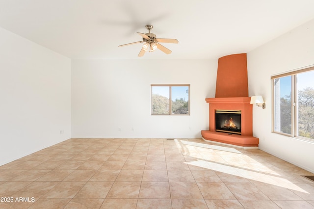 unfurnished living room with ceiling fan, light tile patterned flooring, and a fireplace