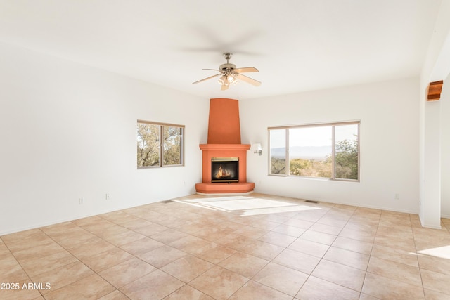 unfurnished living room with a large fireplace, ceiling fan, light tile patterned floors, and visible vents