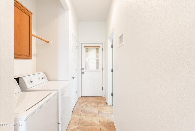 clothes washing area featuring washer and dryer, visible vents, cabinet space, and light tile patterned floors