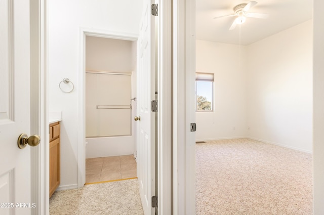 hallway featuring light carpet, light tile patterned floors, and baseboards