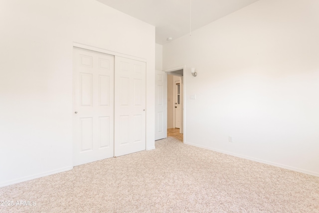 unfurnished bedroom featuring a closet, light carpet, and baseboards