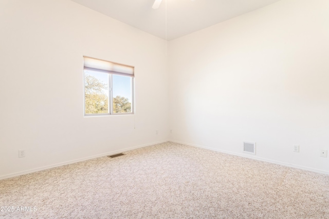 carpeted spare room featuring visible vents, ceiling fan, and baseboards