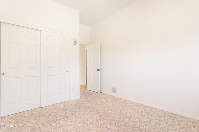 unfurnished bedroom with baseboards, visible vents, a closet, and light colored carpet