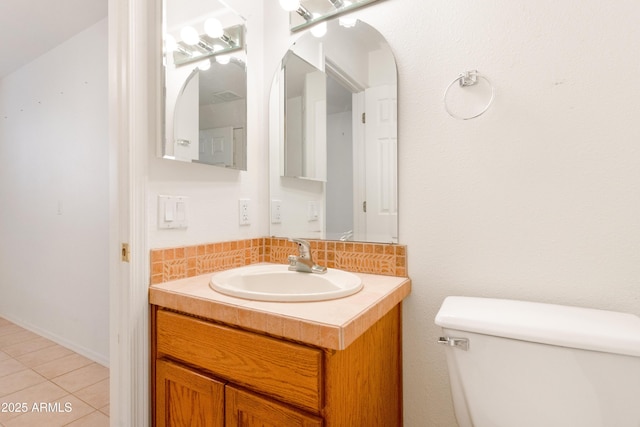 half bathroom with tile patterned flooring, vanity, and toilet