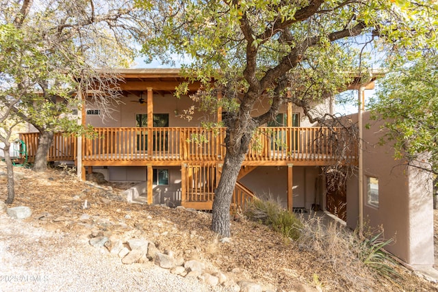 rear view of property with stucco siding, ceiling fan, and a wooden deck