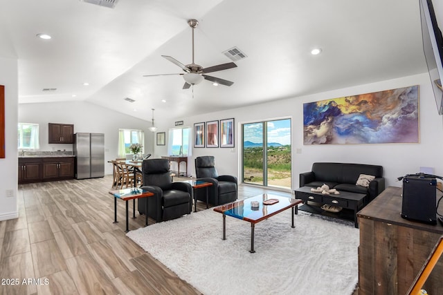 living room with sink, vaulted ceiling, light hardwood / wood-style floors, and ceiling fan