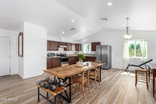 dining room with lofted ceiling, sink, and light wood-type flooring