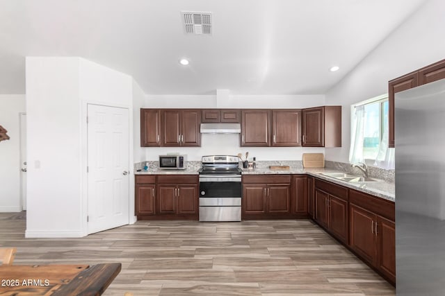 kitchen featuring sink, dark brown cabinets, stainless steel appliances, light stone countertops, and vaulted ceiling