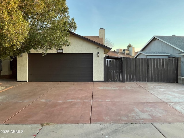 view of side of property featuring a garage, stucco siding, a chimney, central AC unit, and concrete driveway