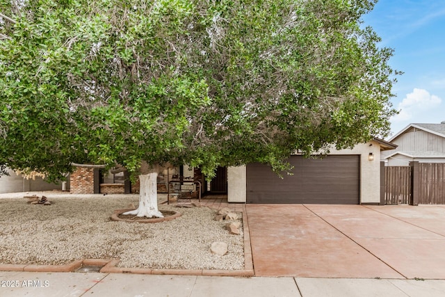 obstructed view of property featuring fence, an attached garage, concrete driveway, and stucco siding
