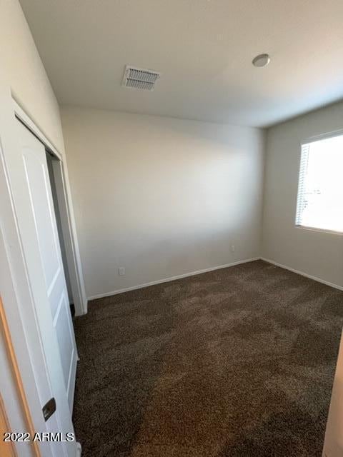 unfurnished room with dark colored carpet