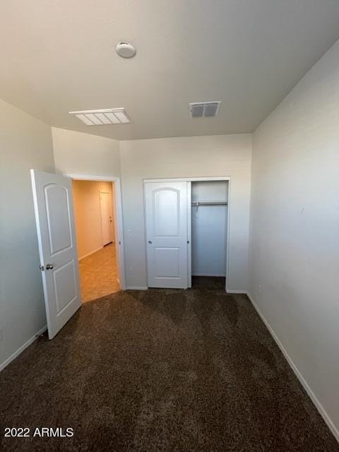 unfurnished bedroom with a closet and dark colored carpet