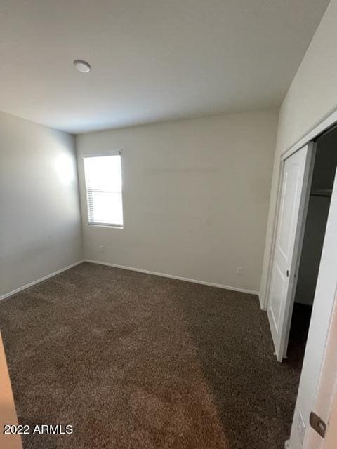 unfurnished bedroom with a closet and dark carpet