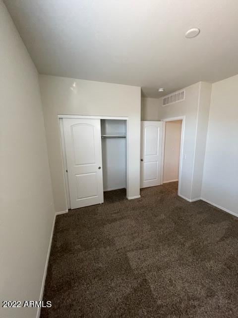 unfurnished bedroom with a closet and dark carpet