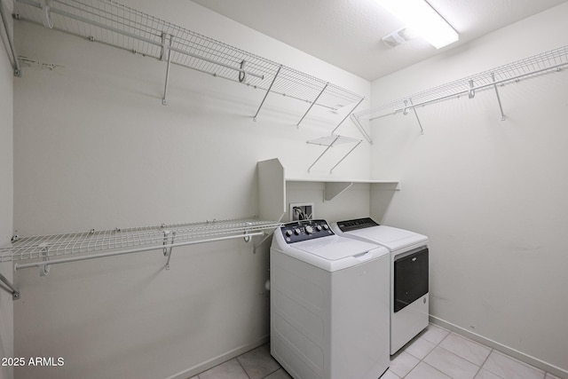 clothes washing area featuring light tile patterned flooring and washing machine and dryer