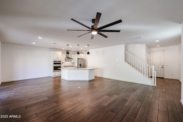 unfurnished living room featuring dark wood-type flooring and ceiling fan