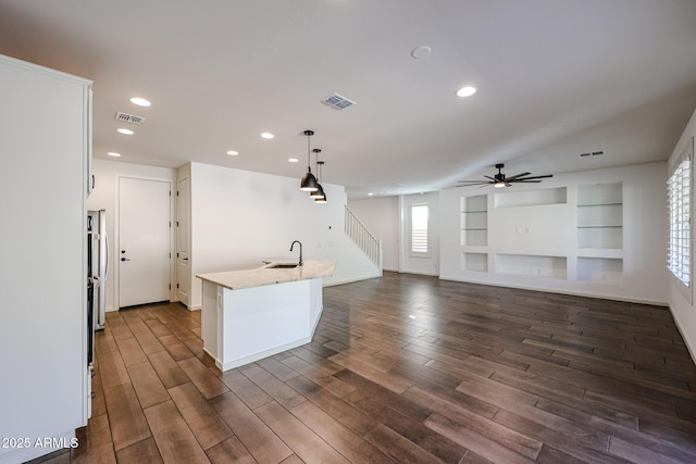 kitchen with white cabinetry, decorative light fixtures, light stone countertops, and a center island with sink