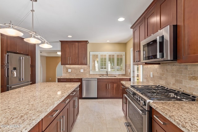 kitchen featuring light stone countertops, sink, hanging light fixtures, tasteful backsplash, and high end appliances