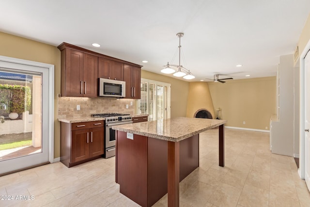 kitchen with a wealth of natural light, ceiling fan, a center island, hanging light fixtures, and stainless steel stove