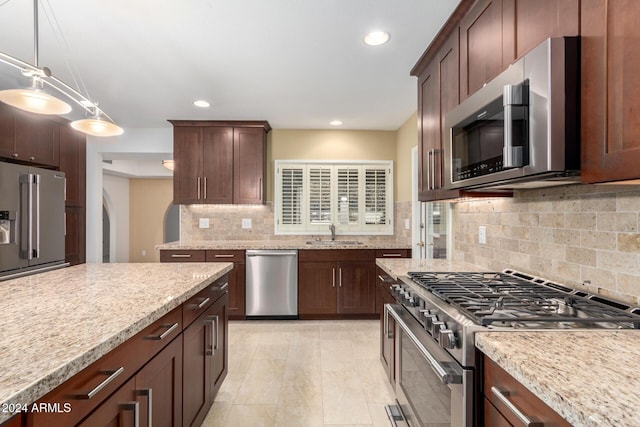 kitchen featuring light stone countertops, sink, hanging light fixtures, tasteful backsplash, and high end appliances