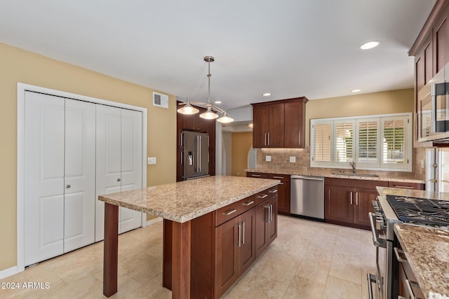 kitchen featuring premium appliances, light stone counters, pendant lighting, decorative backsplash, and a kitchen island