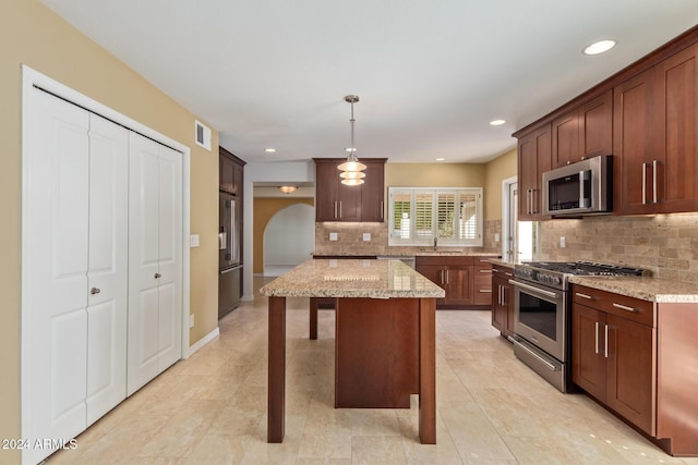 kitchen featuring pendant lighting, a center island, appliances with stainless steel finishes, and tasteful backsplash