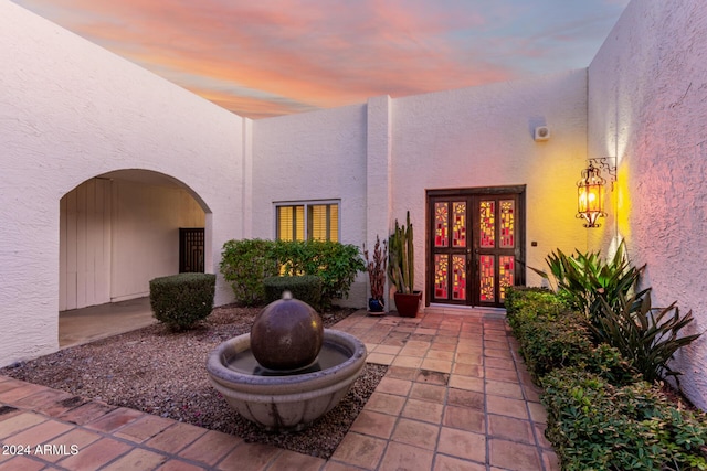 exterior entry at dusk with a patio area and french doors