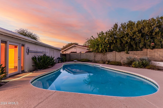 pool at dusk featuring a patio