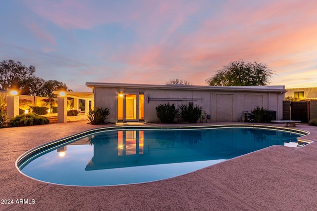 pool at dusk featuring a patio area