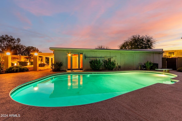 pool at dusk featuring a diving board