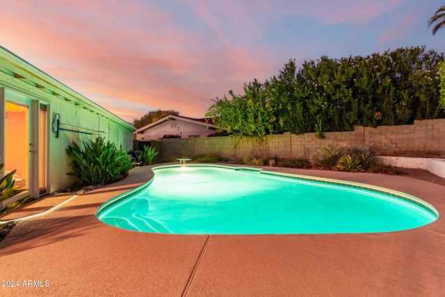 pool at dusk featuring a patio