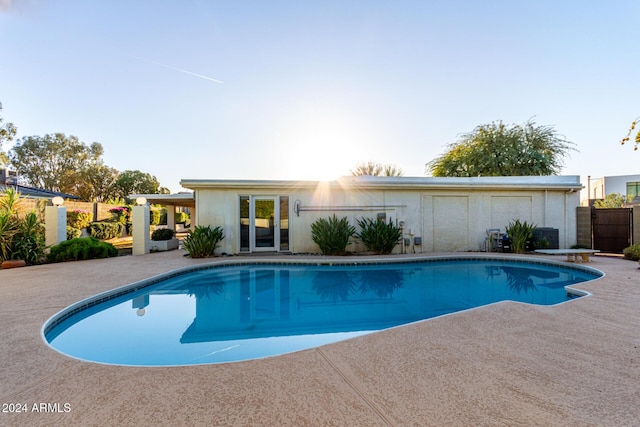 view of swimming pool with a diving board and a patio