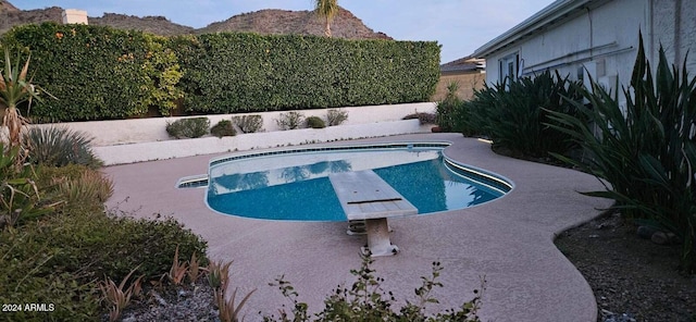 view of pool featuring a mountain view, a diving board, and a patio area