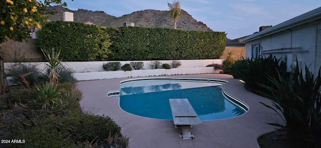 view of pool featuring a mountain view, a diving board, and a patio