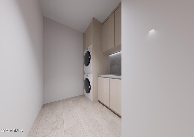 clothes washing area featuring stacked washer and clothes dryer, cabinets, and light hardwood / wood-style floors