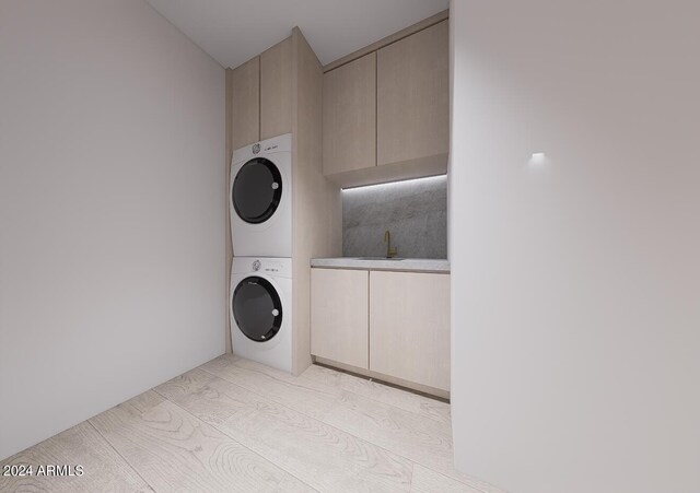 clothes washing area with cabinets, light wood-type flooring, stacked washer / dryer, and sink