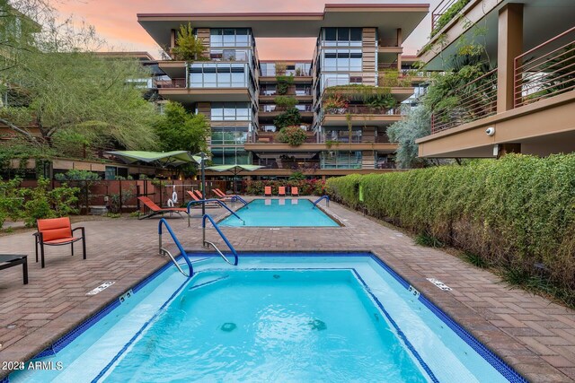 pool at dusk featuring a patio