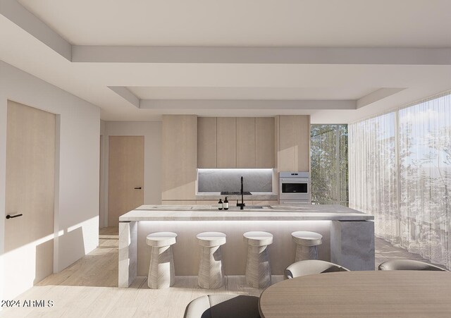 kitchen featuring light hardwood / wood-style floors, sink, oven, a tray ceiling, and a kitchen bar