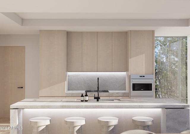 kitchen featuring light brown cabinetry, a breakfast bar area, and oven