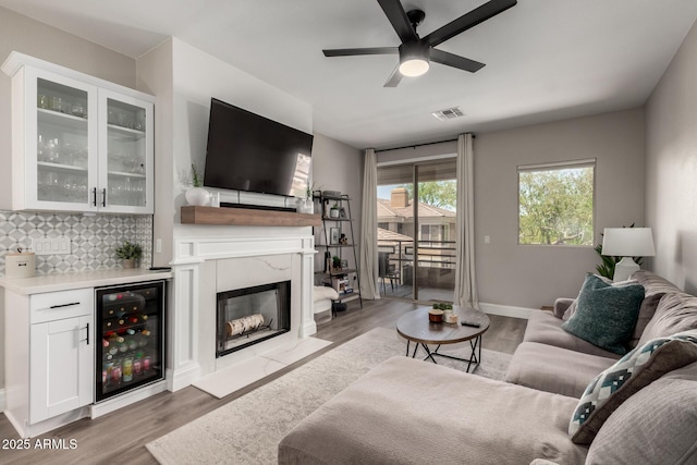 1411 E Orangewood Ave Unit 233, Phoenix, AZ 85020 - living room featuring wine cooler, light wood-style flooring, ceiling fan, a premium fireplace, and baseboards