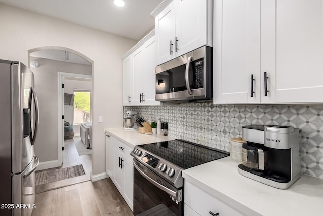 1411 E Orangewood Ave Unit 233, Phoenix, AZ 85020 - kitchen with appliances with stainless steel finishes, arched walkways, wood finished floors, light countertops, and white cabinets