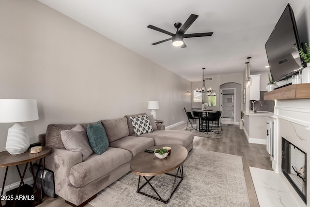 1411 E Orangewood Ave Unit 233, Phoenix, AZ 85020 - living room with a ceiling fan, arched walkways, light wood-style flooring, and baseboards